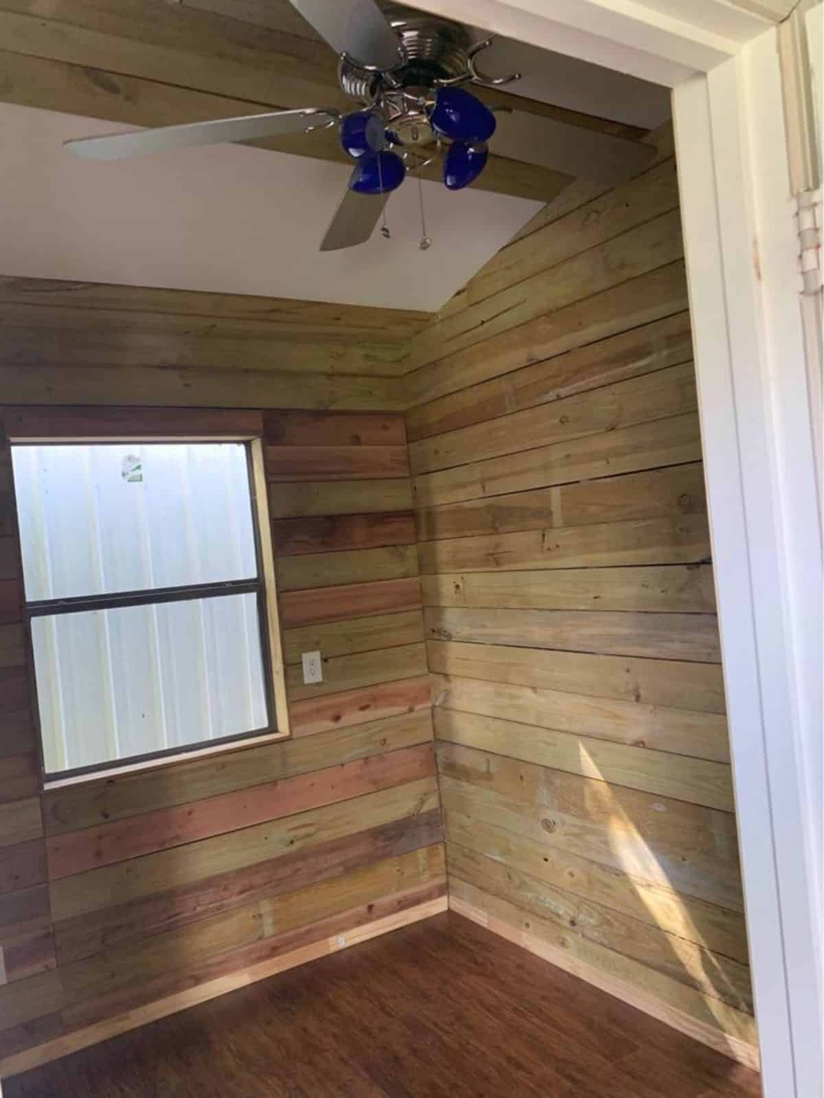 small bedroom has a wooden walls with a storage
