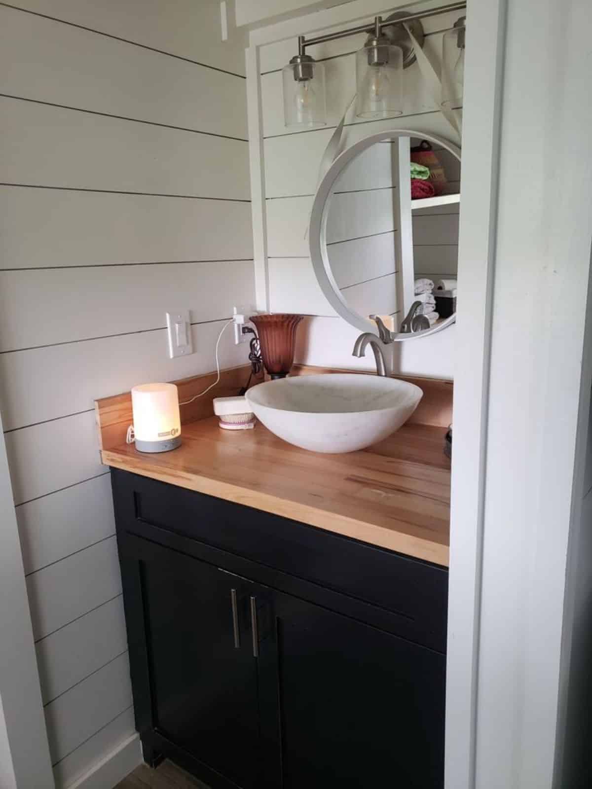 sink with vanity and mirror in bathroom of stunning 28’ tiny house