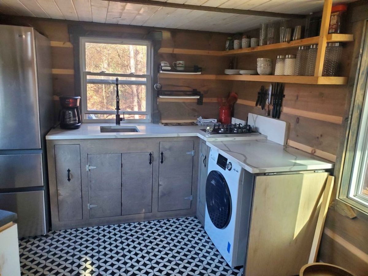 L shaped kitchen area with storage cabinets of offgrid tiny home