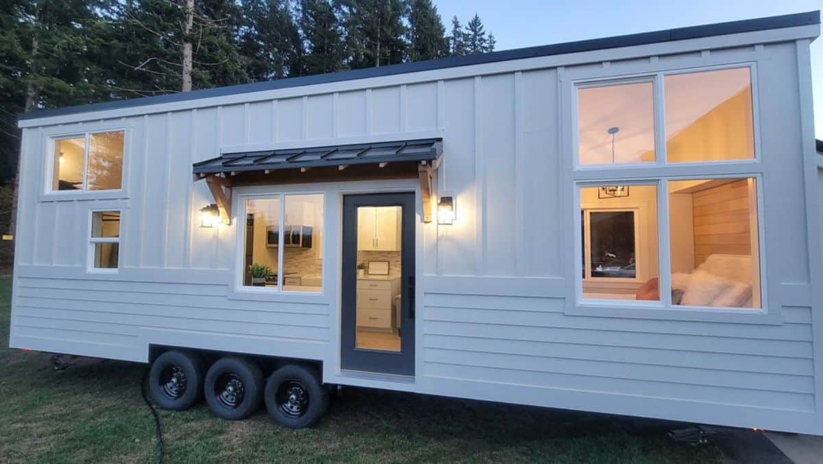 stunning white exterior with huge windows of custom built tiny home