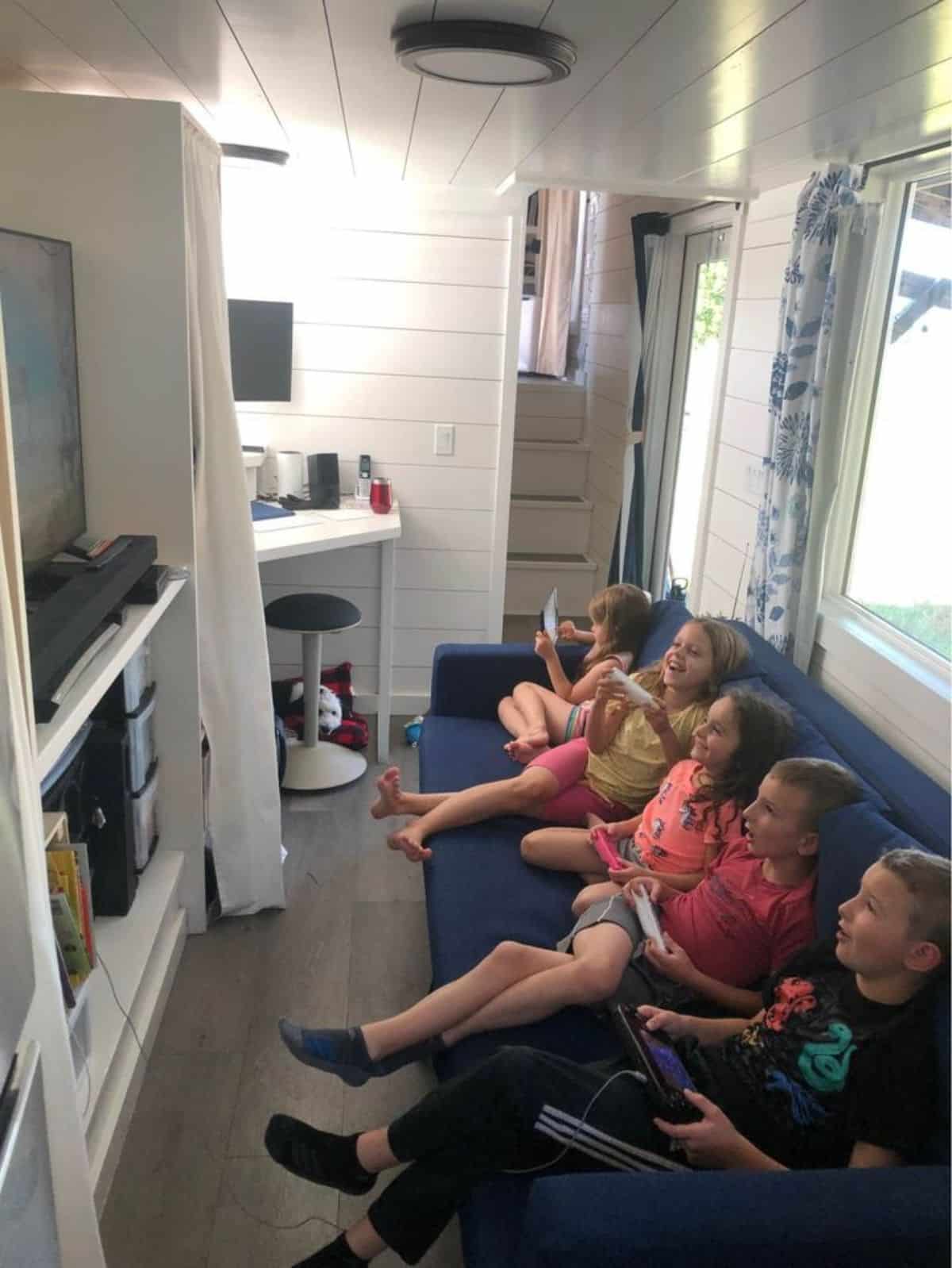 living area of tiny home for four has a comfortable couch, entertainment unit with TV
