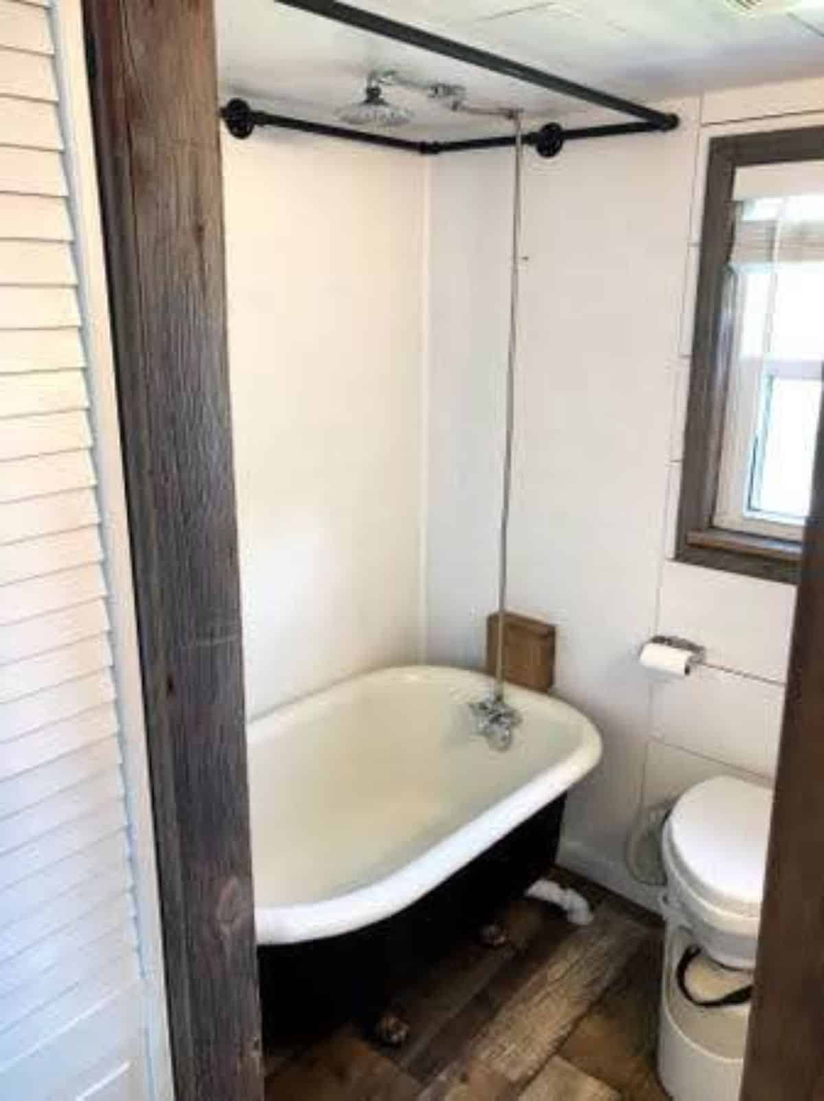 composting toilet and a bathtub in bathroom of 24' fully furnished tiny home