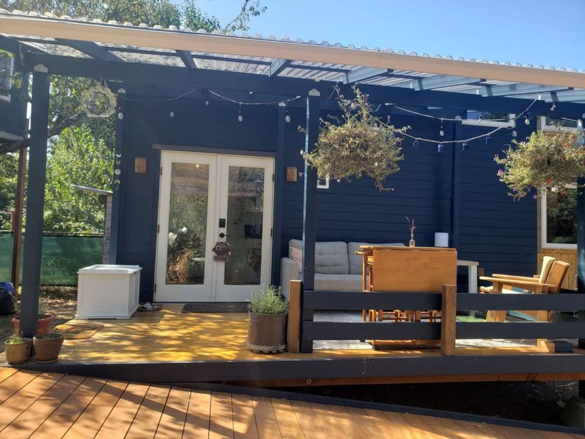 stunning dark blue exterior with huge porch outside the 24’ tiny home