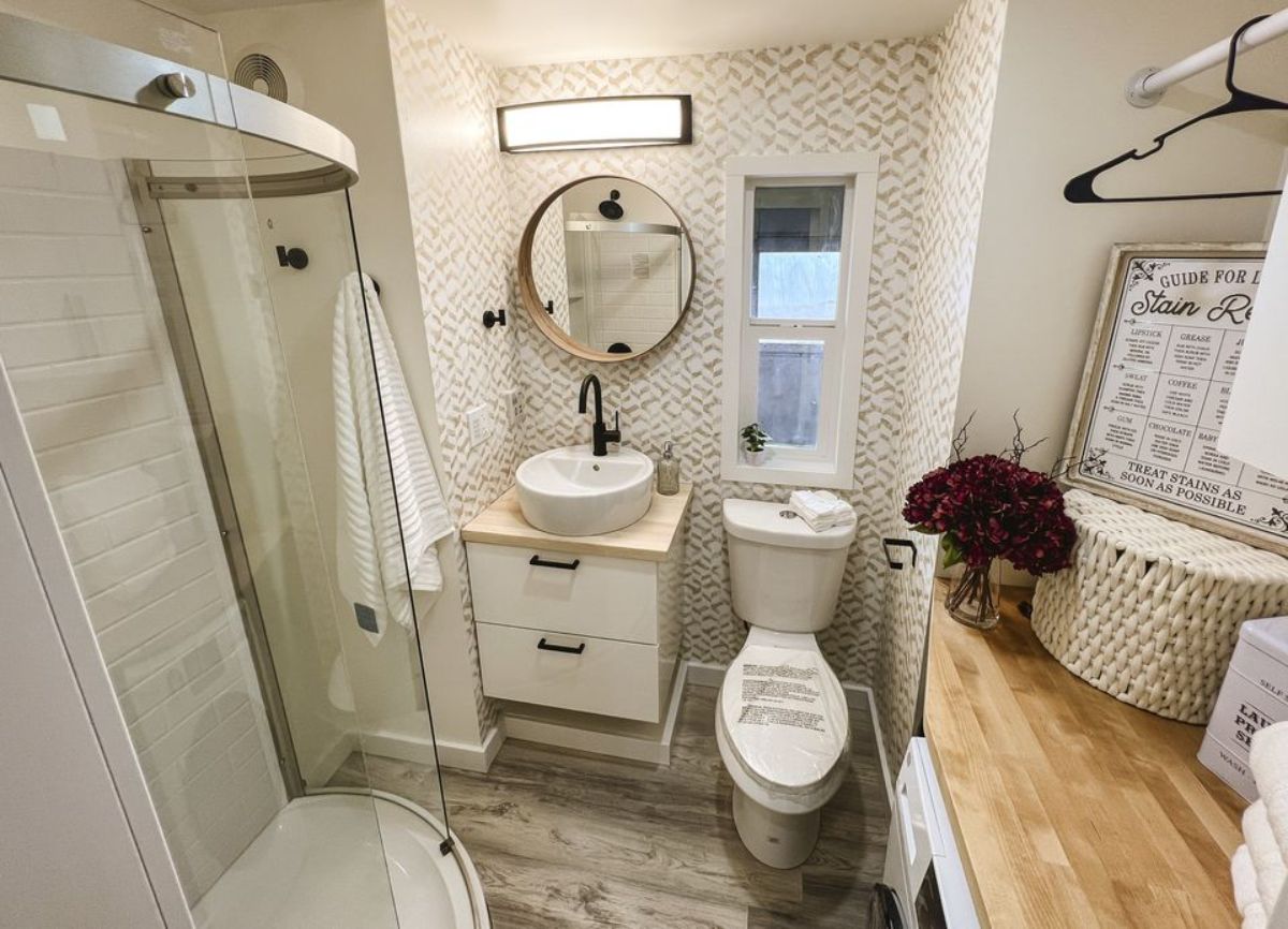 bathroom of 26’ tiny home has all the standard fittings with glass enclosure shower