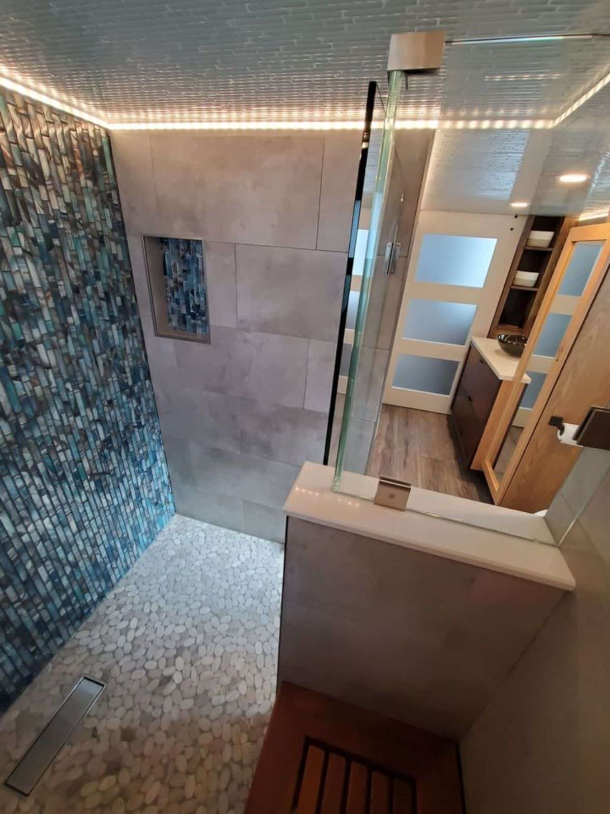 separate shower area with rain shower and sink with vanity and mirror
