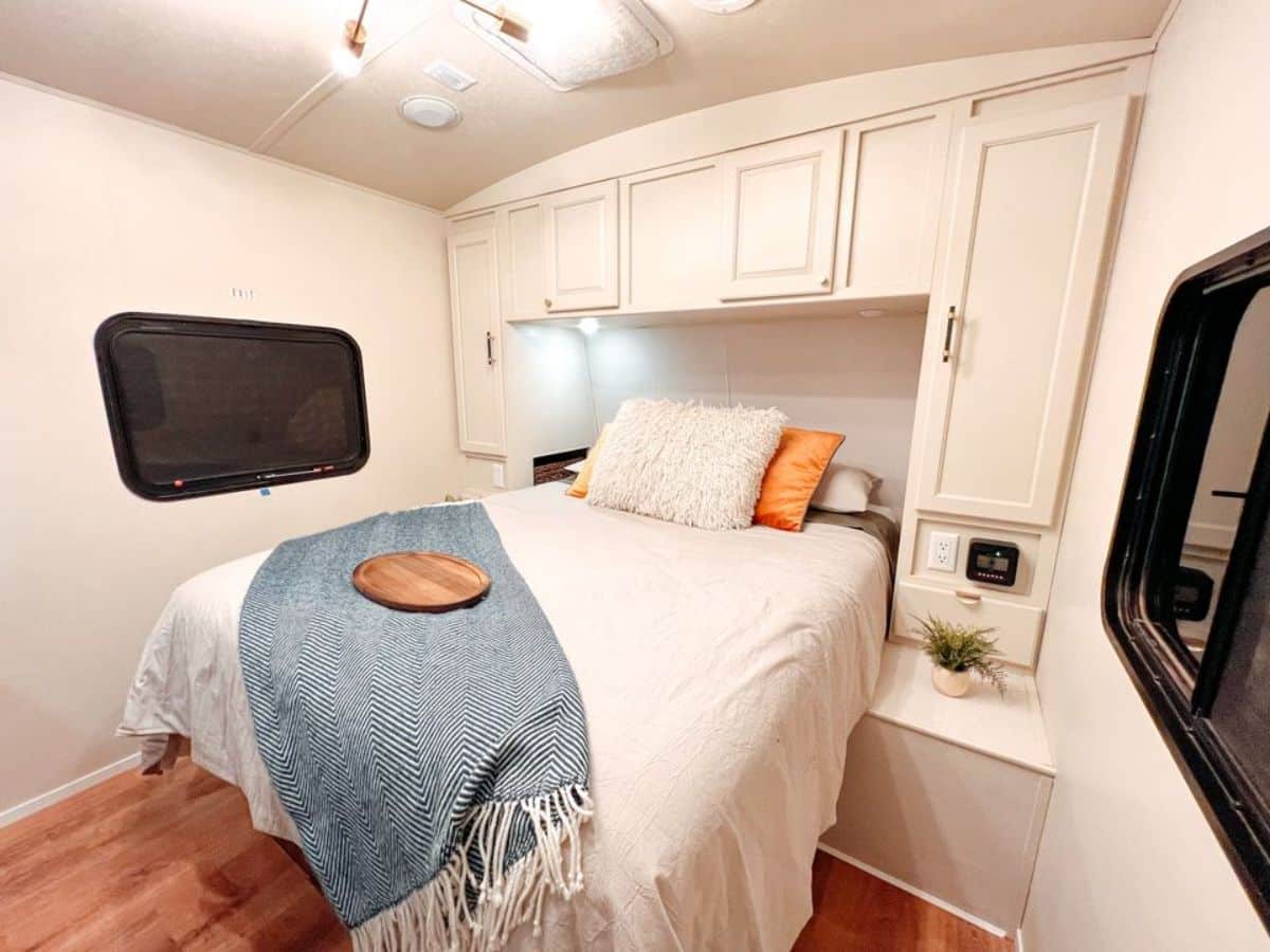 bedroom of redesigned tiny home has a comfortable double bed, storage cabinets, side table and LED lights installed