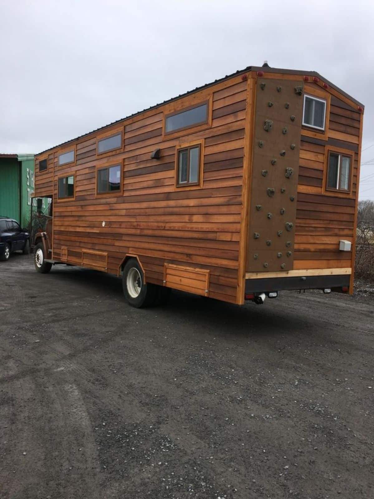 backside has a rock climbing wall and sides with multiple windows of rustic motorhome
