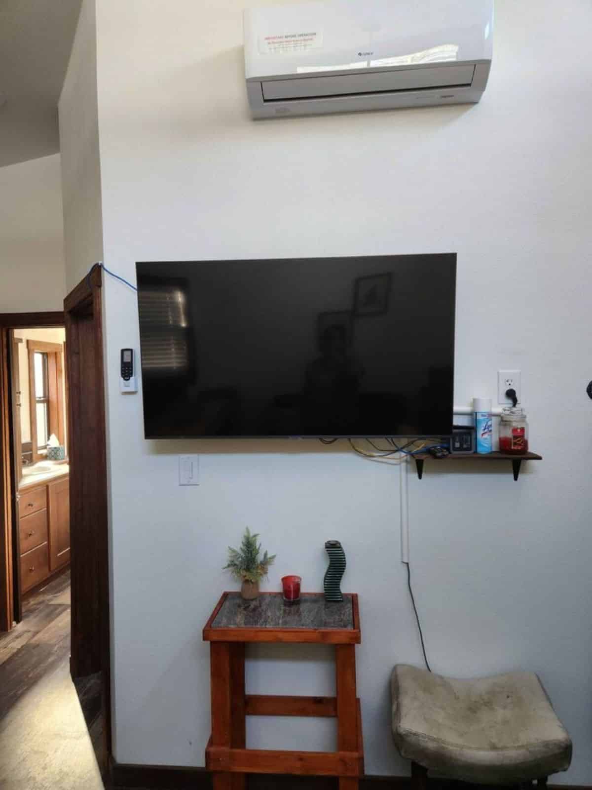 wall mounted TV set with air condition unit in living area of cottage tiny home
