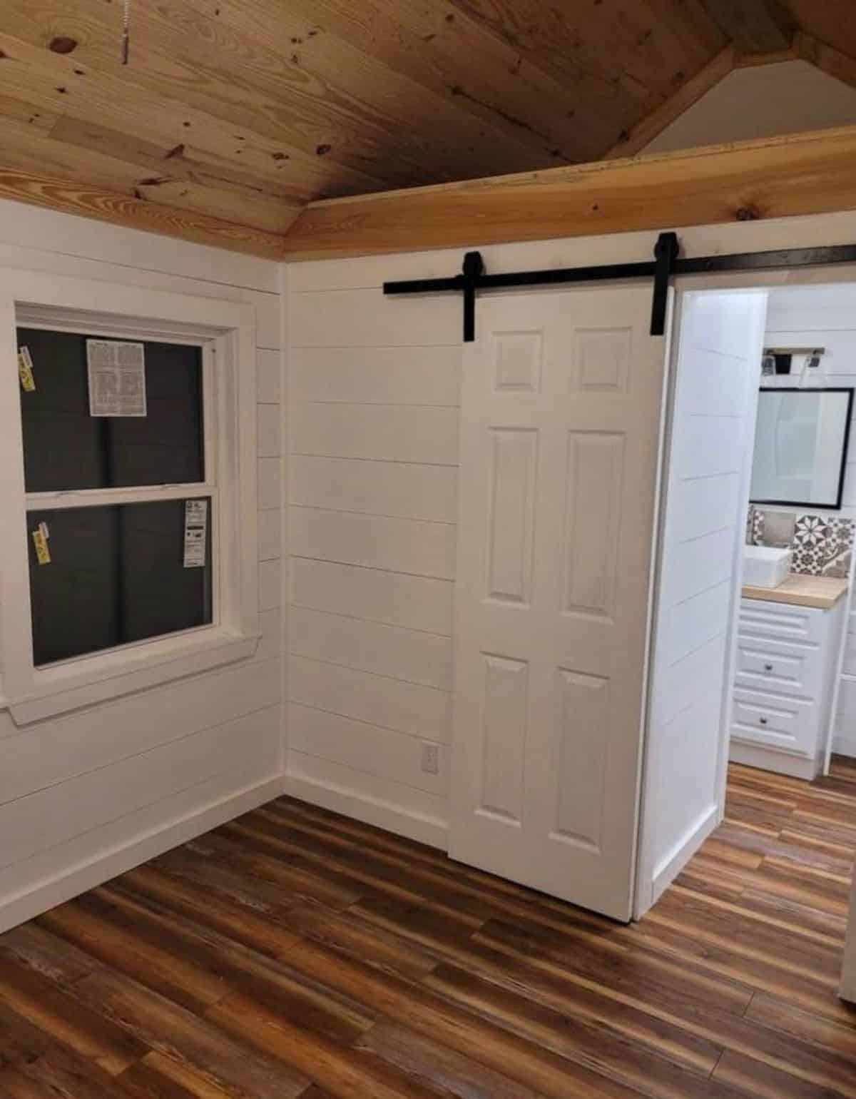 bedroom of 40' spacious tiny house is spacious with sliding door