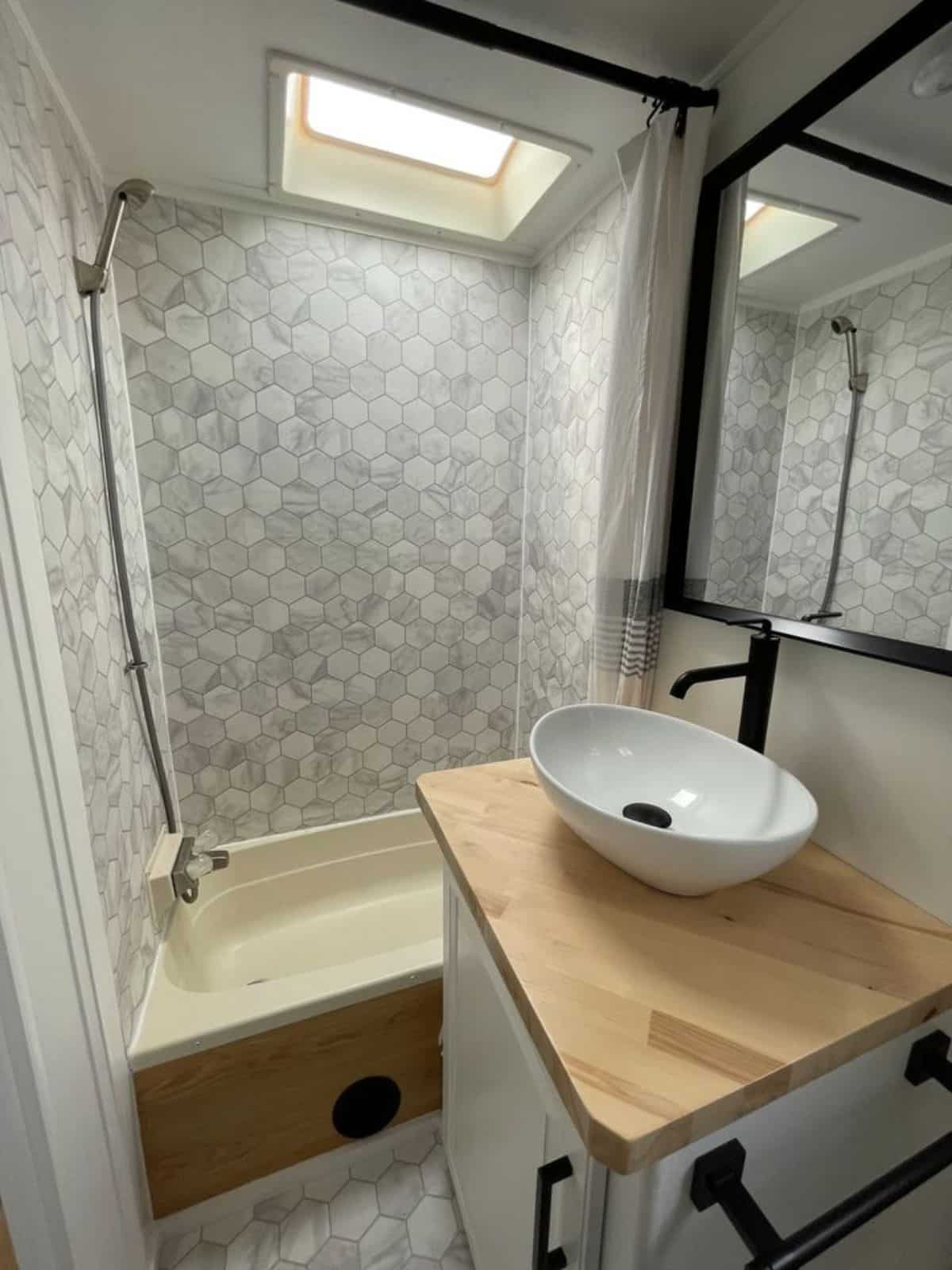 full length shower cum bathtub and sink with vanity with mirror in bathroom of 5th wheel trailer home