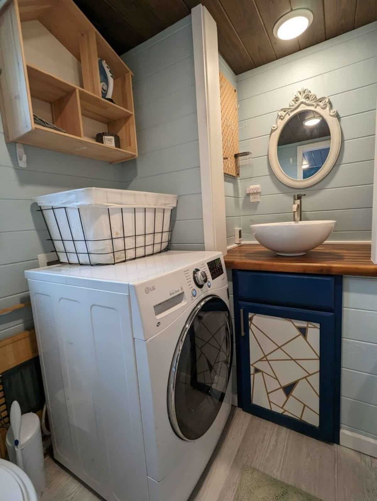 sink with vanity & mirror, washer dryer combo and storage in bathroom of custom home on wheels