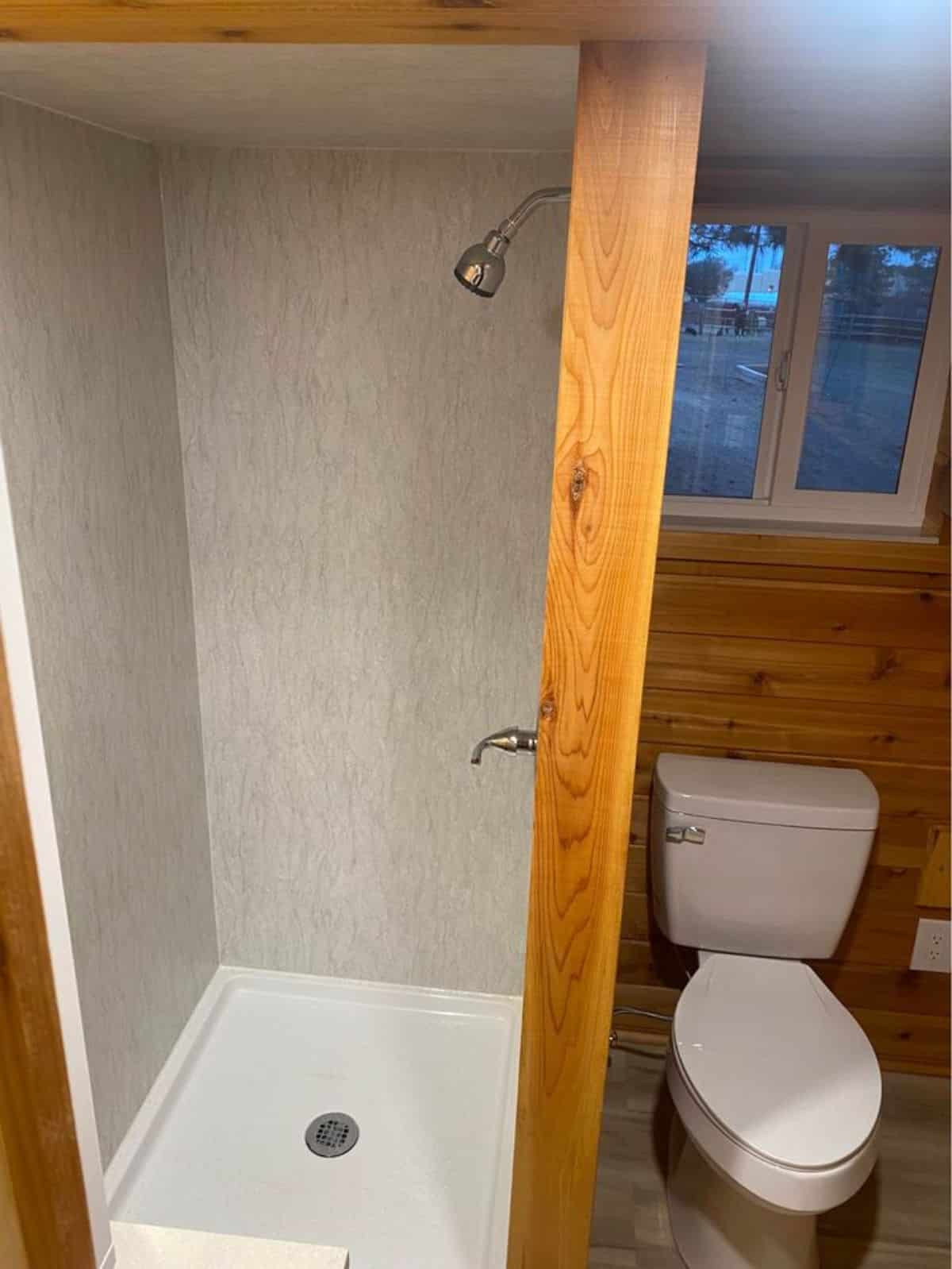 standard toilet, full length shower area in bathroom of double lofted tiny home