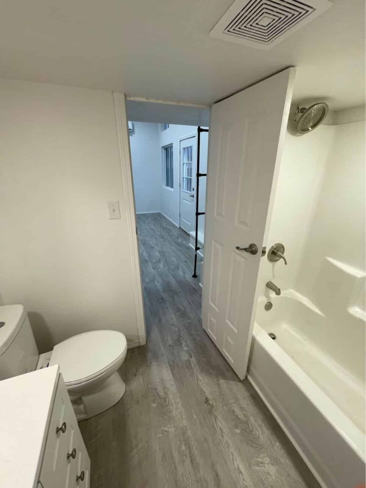 standard toilet and bathtub in bathroom of 24’ modern tiny home