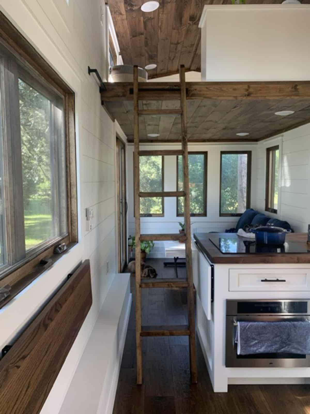 collapsible folding table under the window and ladder leading to the loft of gooseneck tiny home