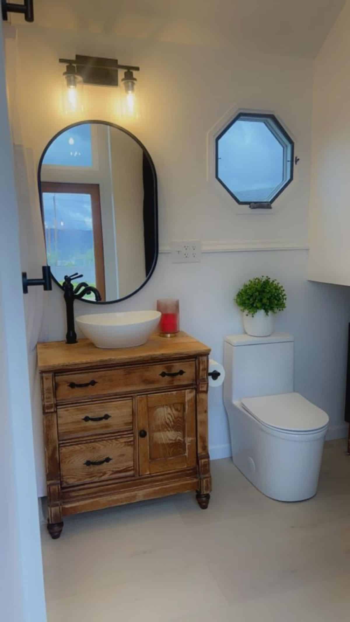 bathroom of spacious tiny home has all the standard fittings with huge mirror