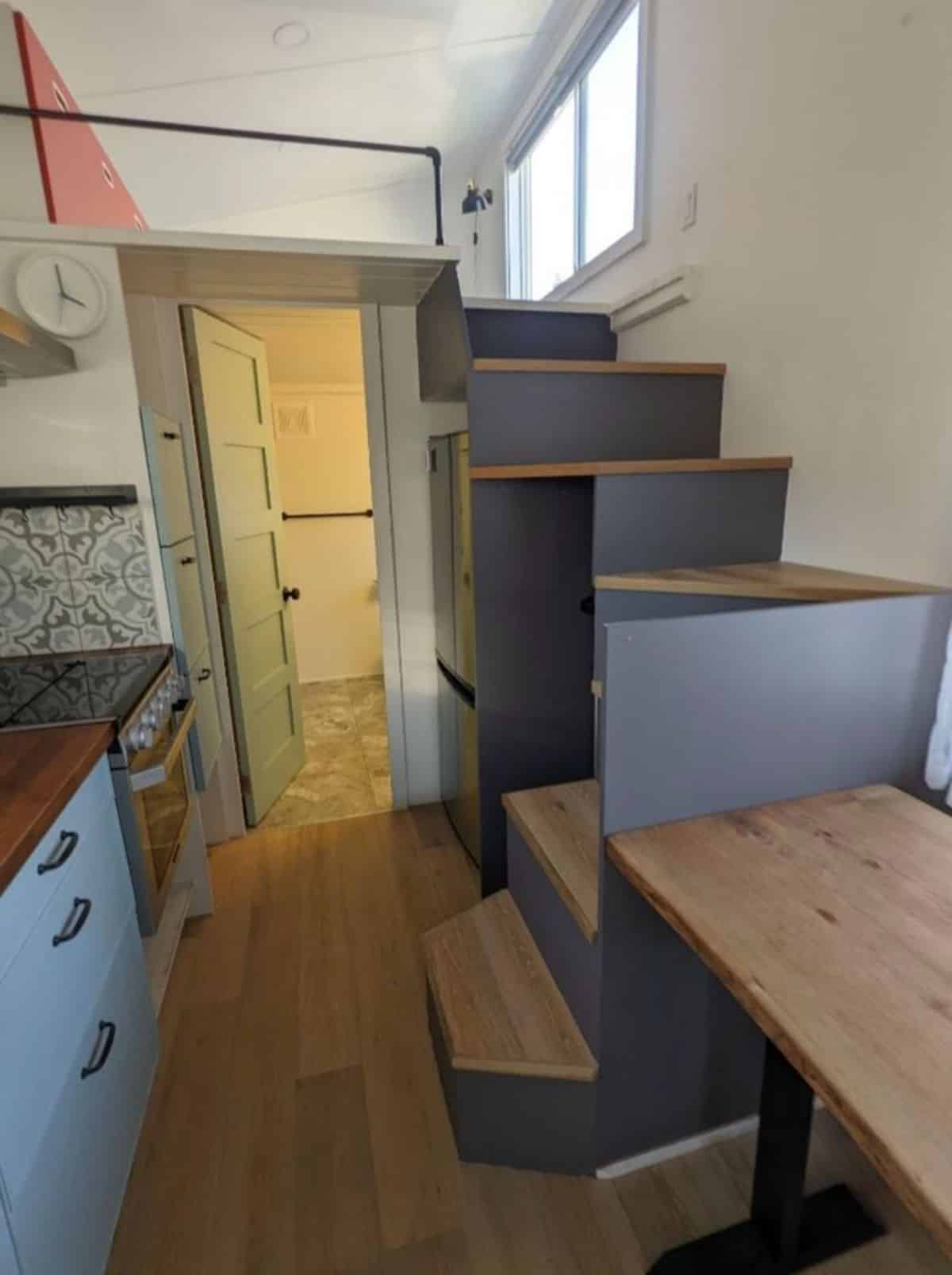 multi purpose stairs has refrigerator underneath and it leads to the main loft