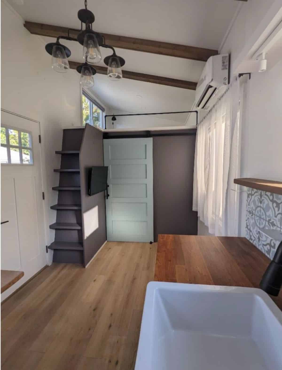 living area opposite to the main entrance door is small  and stunning stairs leading to loft 2 of three bedroom tiny house