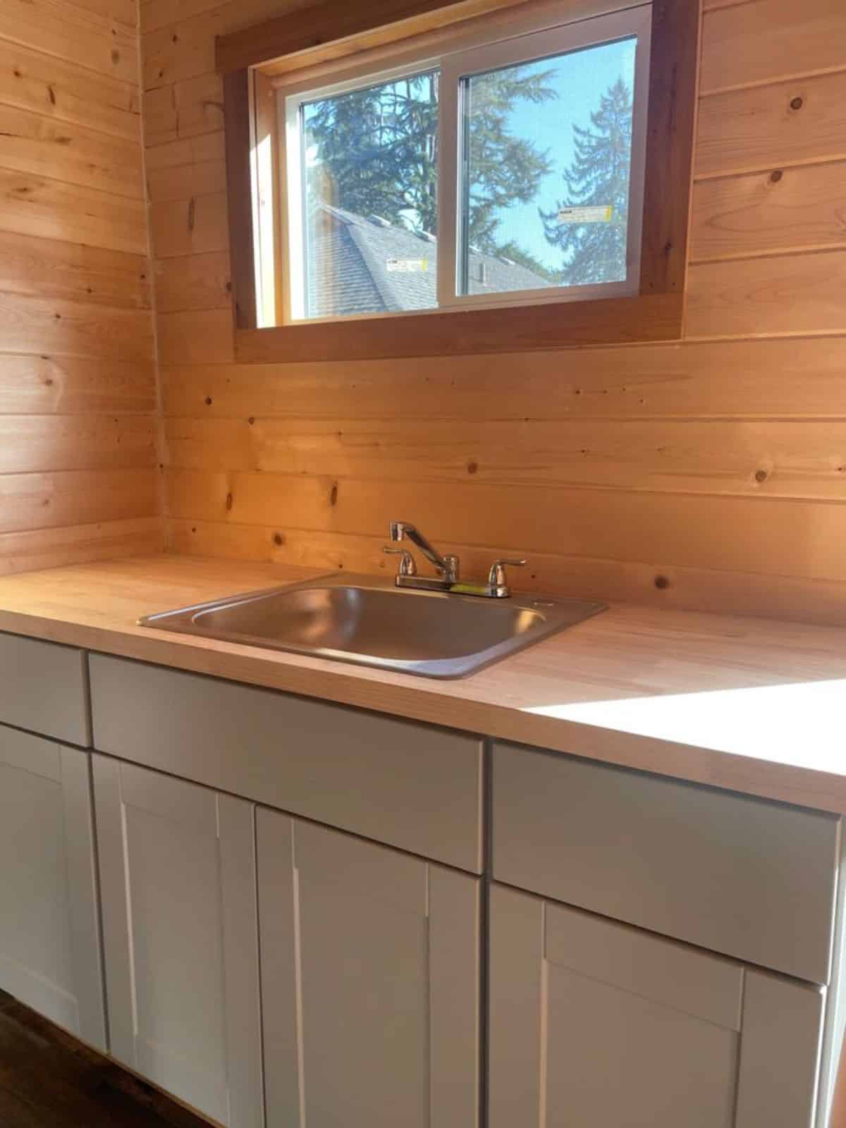 huge countertop with stainless steel sink and multiple storage cabinets in kitchen of 20' tiny trailer house