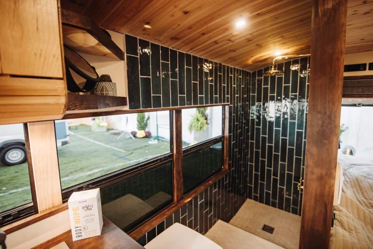 full length black tiled rain shower area with composting toilet in bathroom