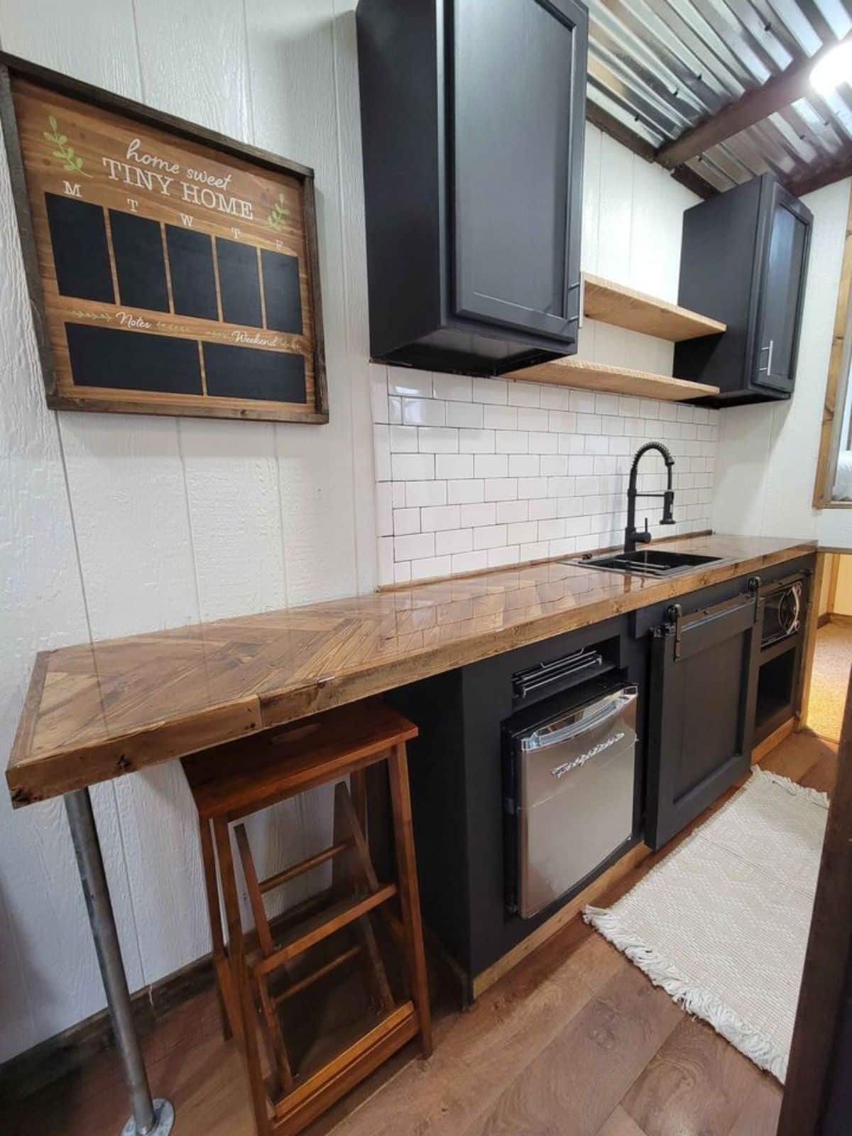 wooden shelves, storage cabinets, essential appliances and long kitchen counter top with an extension being dining table