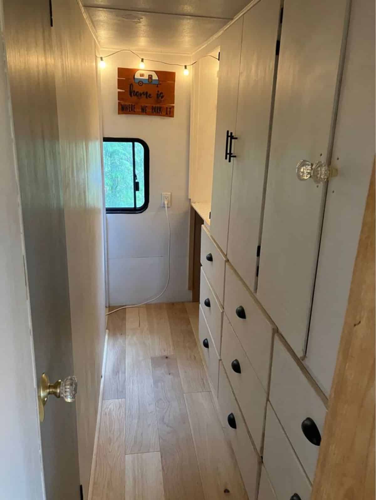hallway path between living area and bedroom is occupied with storage cabinets