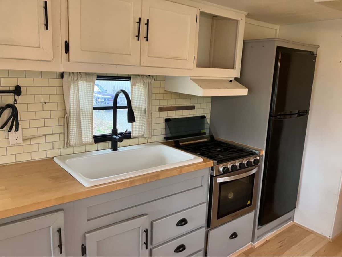 kitchen area of revamped tiny home has a huge countertop and all the necessary appliances