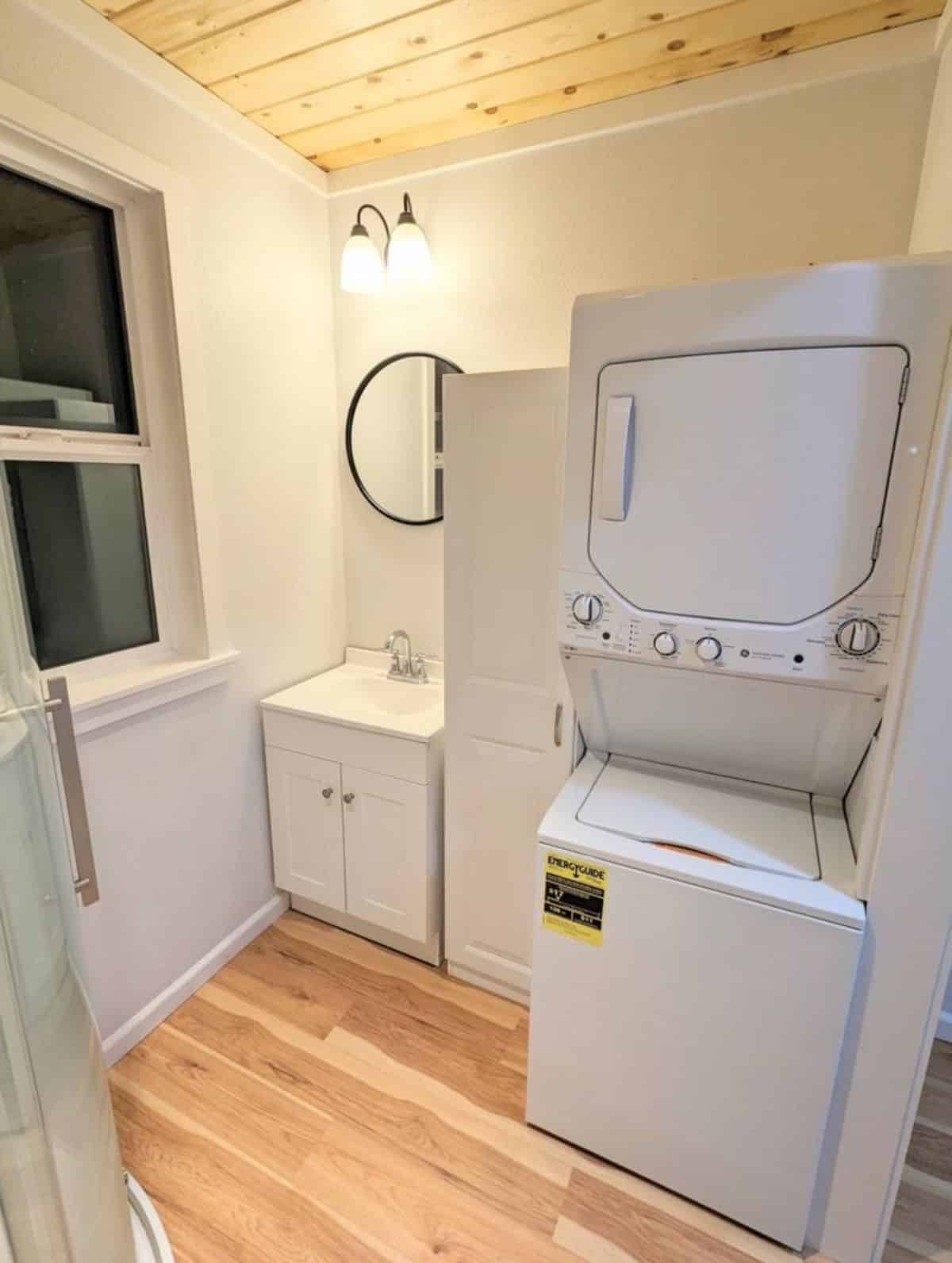 sink with vanity and mirror and huge washer dryer combo in bathroom