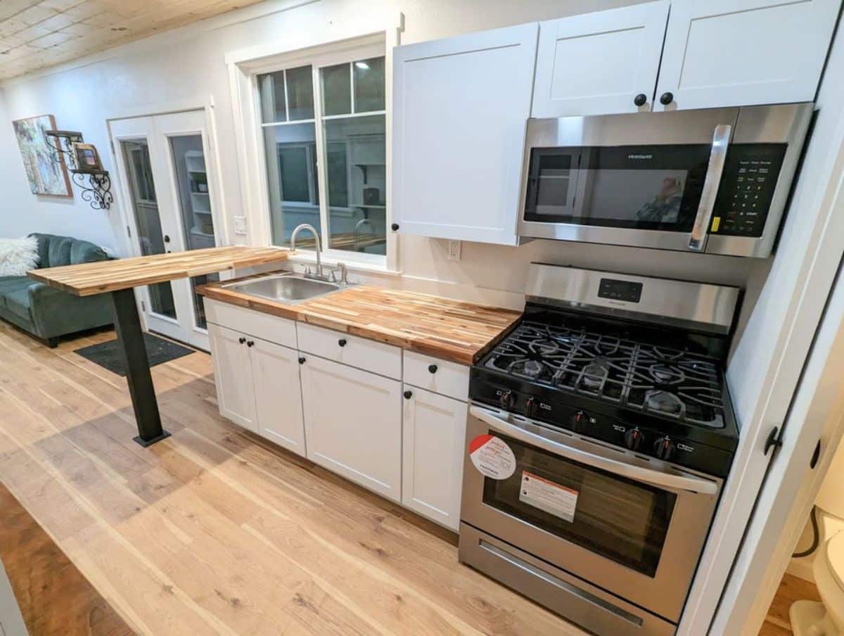 well organized kitchen area of 40’ custom tiny home has all the essential appliances and storage