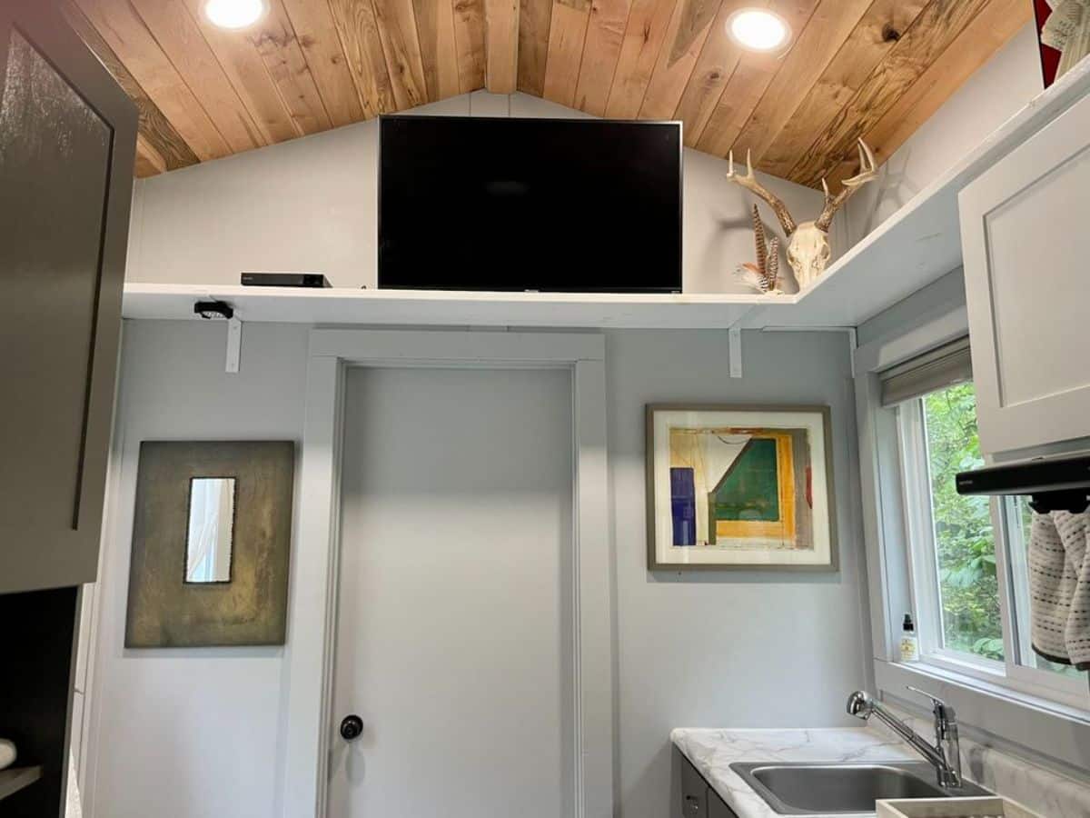 huge TV unit installed above the bathroom door opposite to the living area