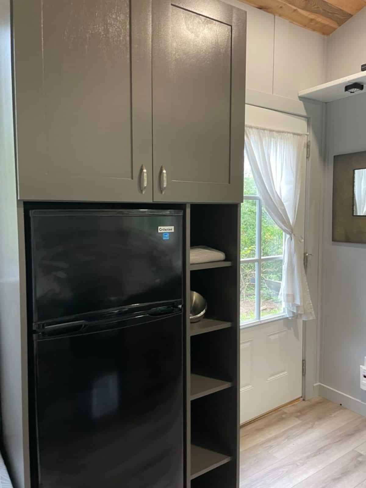 storage shelves and cabinets with full length refrigerator opposite to kitchen area of high end tiny home