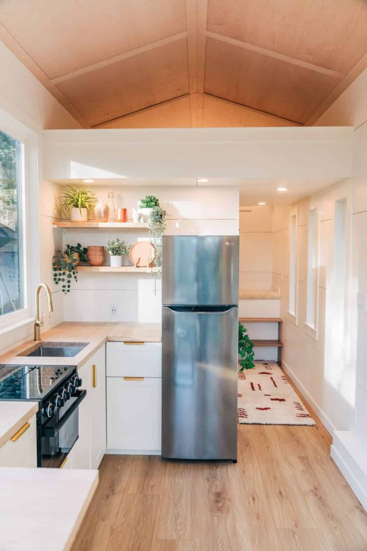 double door refrigerator and propane gas stove in kitchen area of beautifully crafted tiny home