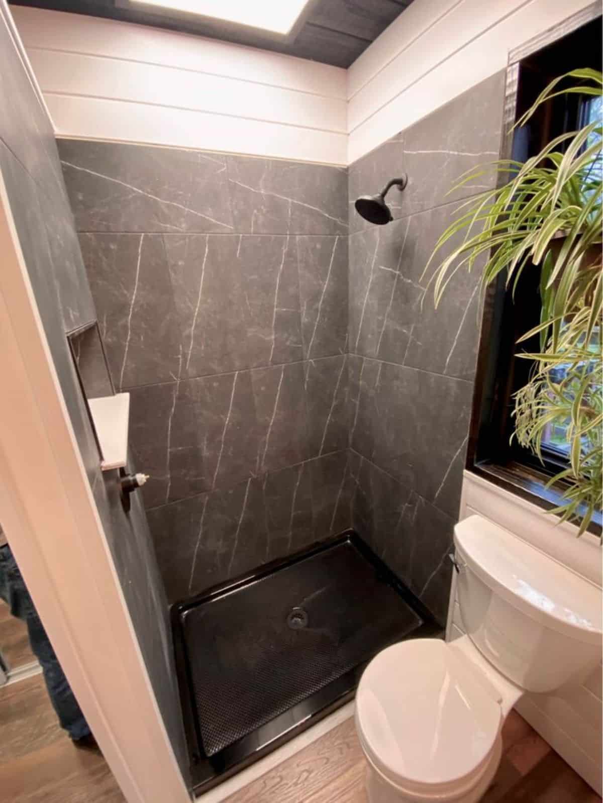 full length shower area with rain shower and standard toilet in bathroom