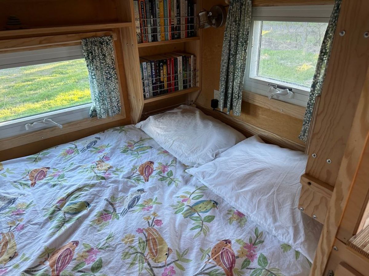 double bed sleeping area with storage and book shelves