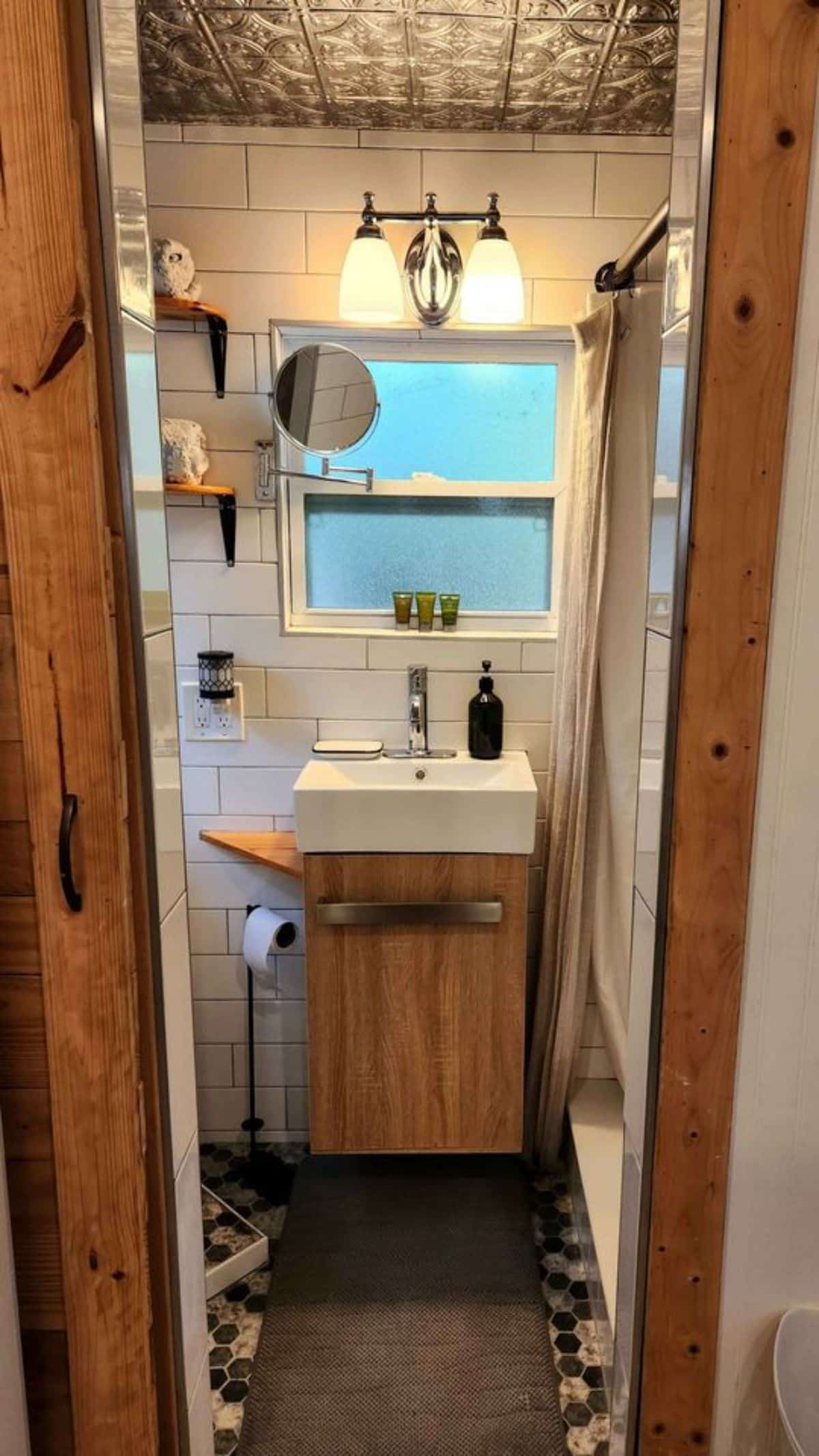 sink with vanity and small mirror in bathroom of rustic mini home