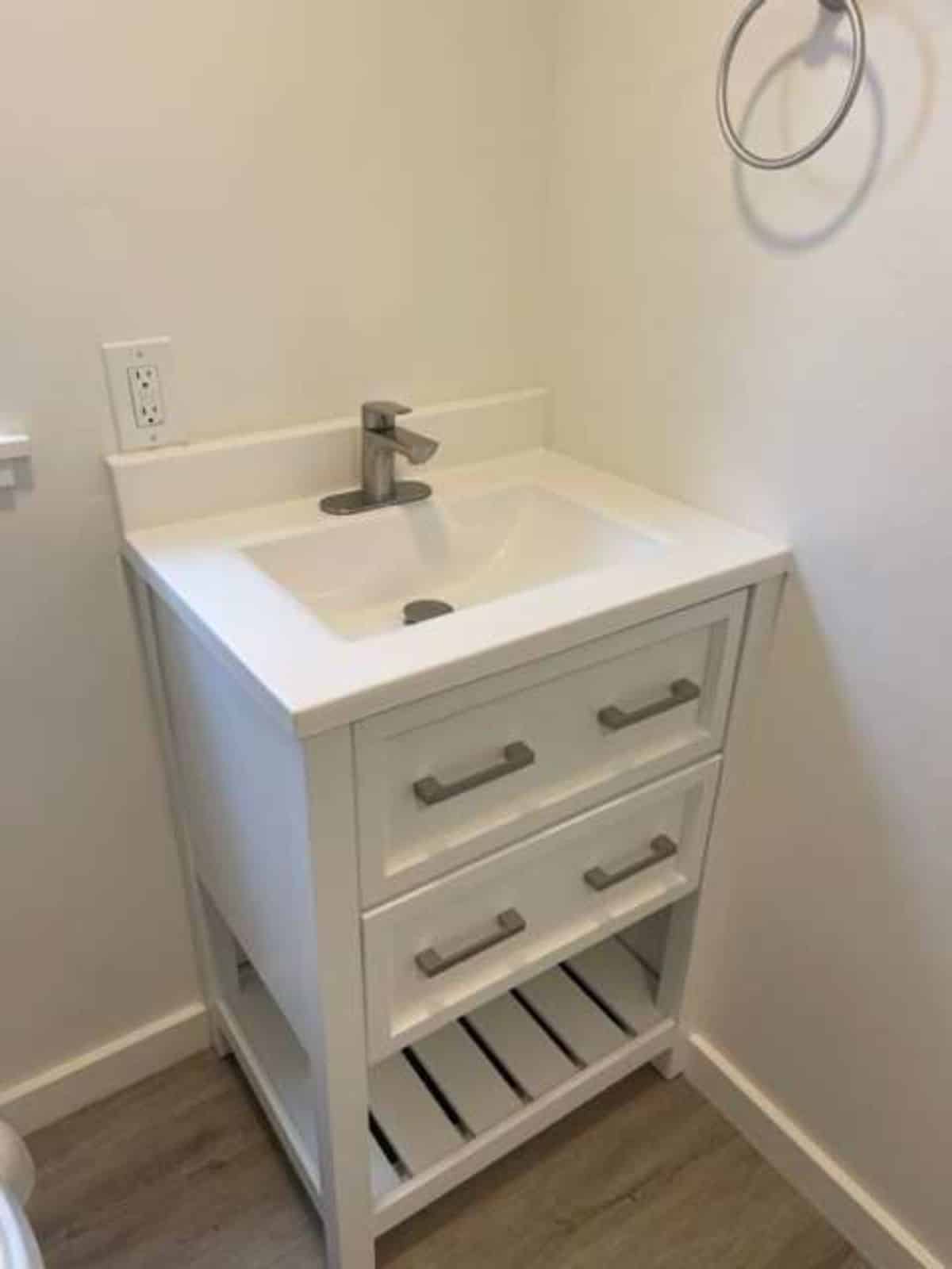 sink with vanity and other storage cabinets in bathroom of tiny home with a loft