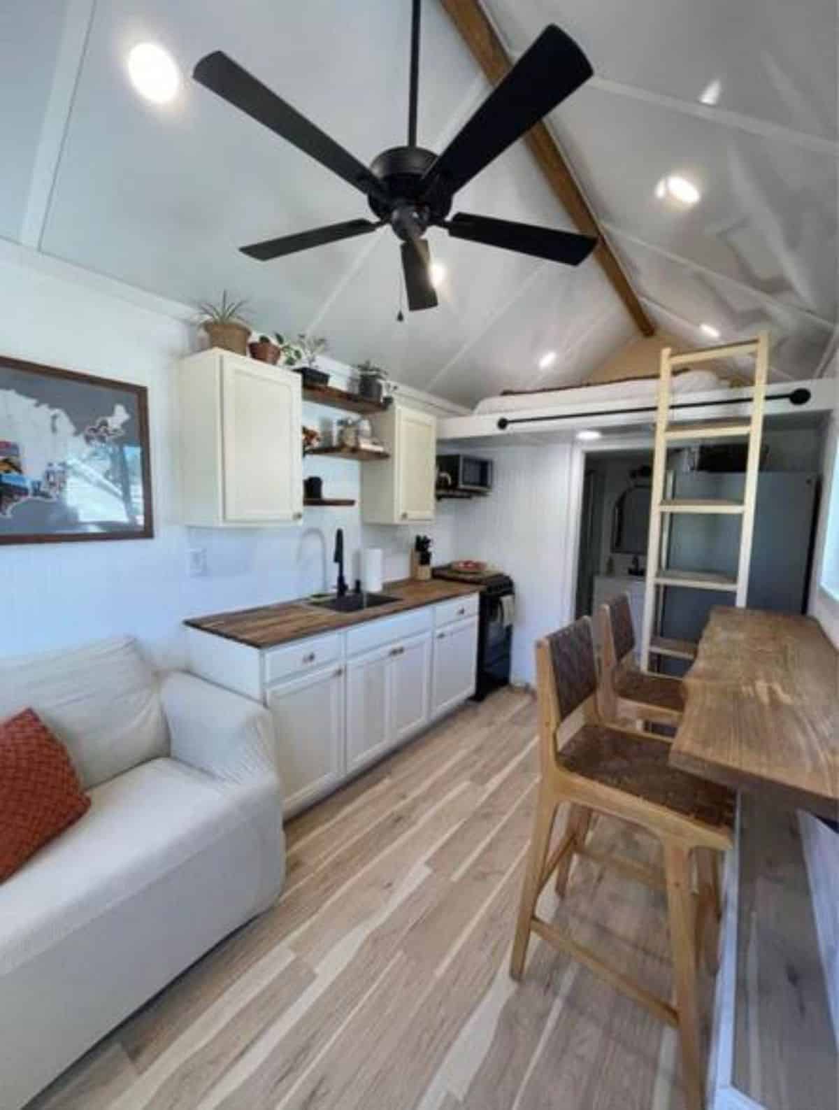 living area of 16' chic tiny home has a couch and dining table with chairs on the opposite side