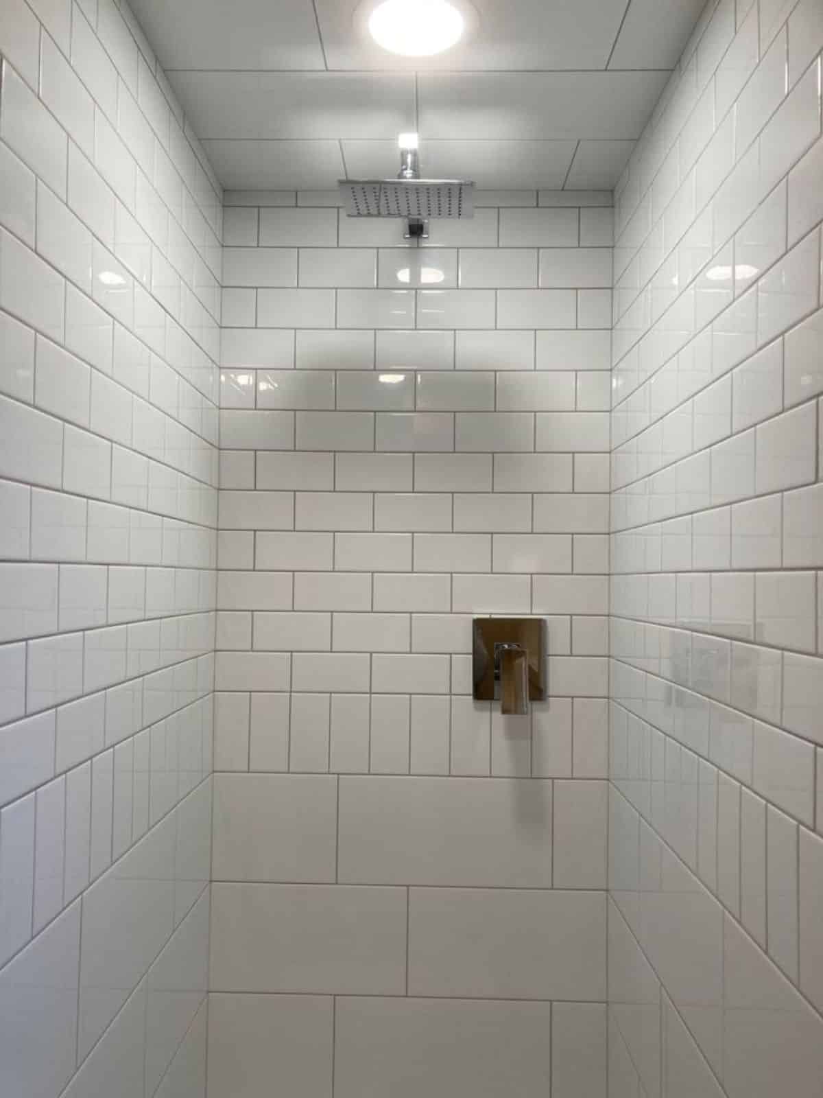 full length white tiled shower area in bathroom