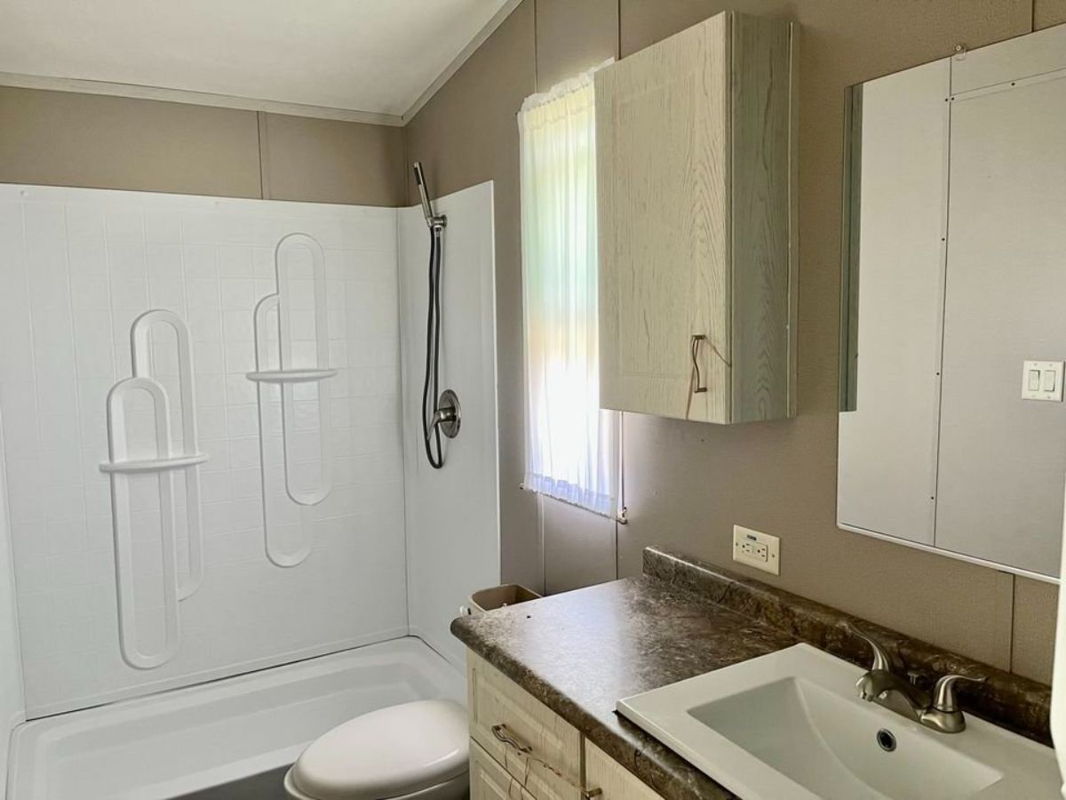 sink with vanity and mirror and standard toilet with bathtub and shower