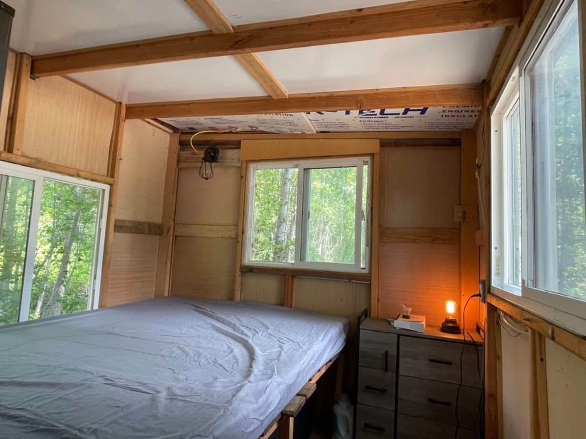 double bed with wardrobe and storage in bedroom of rustic tiny house
