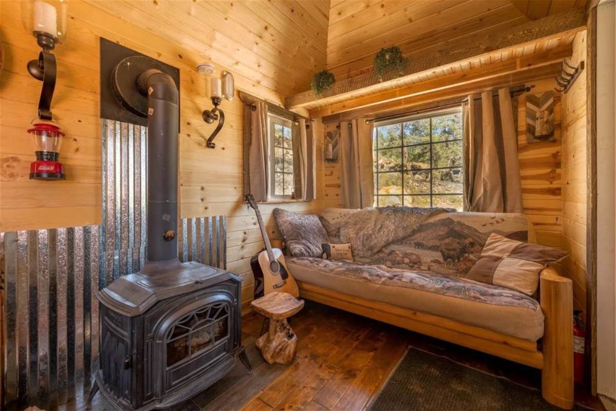 living area of 28' rustic tiny home has a couch, fireplace