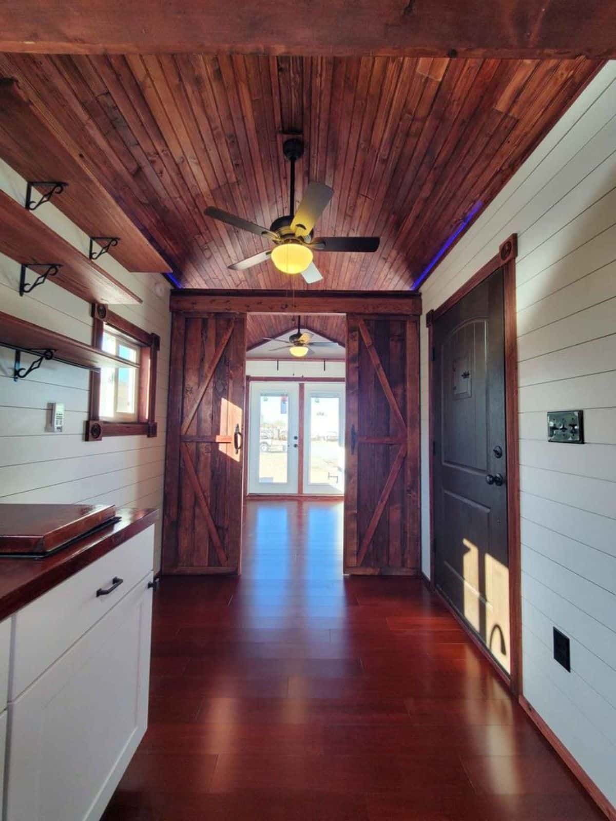 shelves in the kitchen area and an amazing fan at the entrance main door of 24' tiny home on wheels