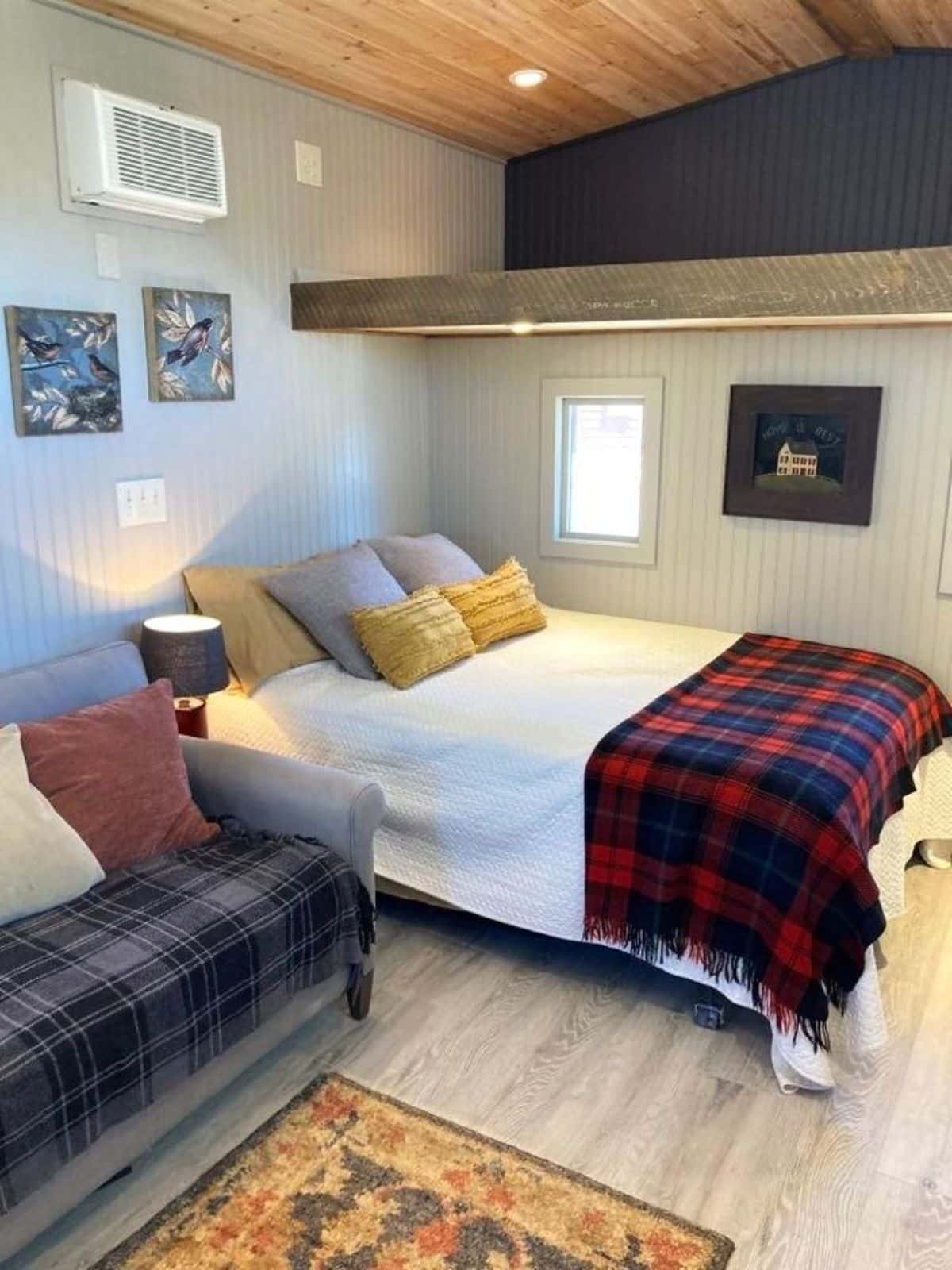 sleeping area of custom mobile home has a comfortable bed and a loft above it