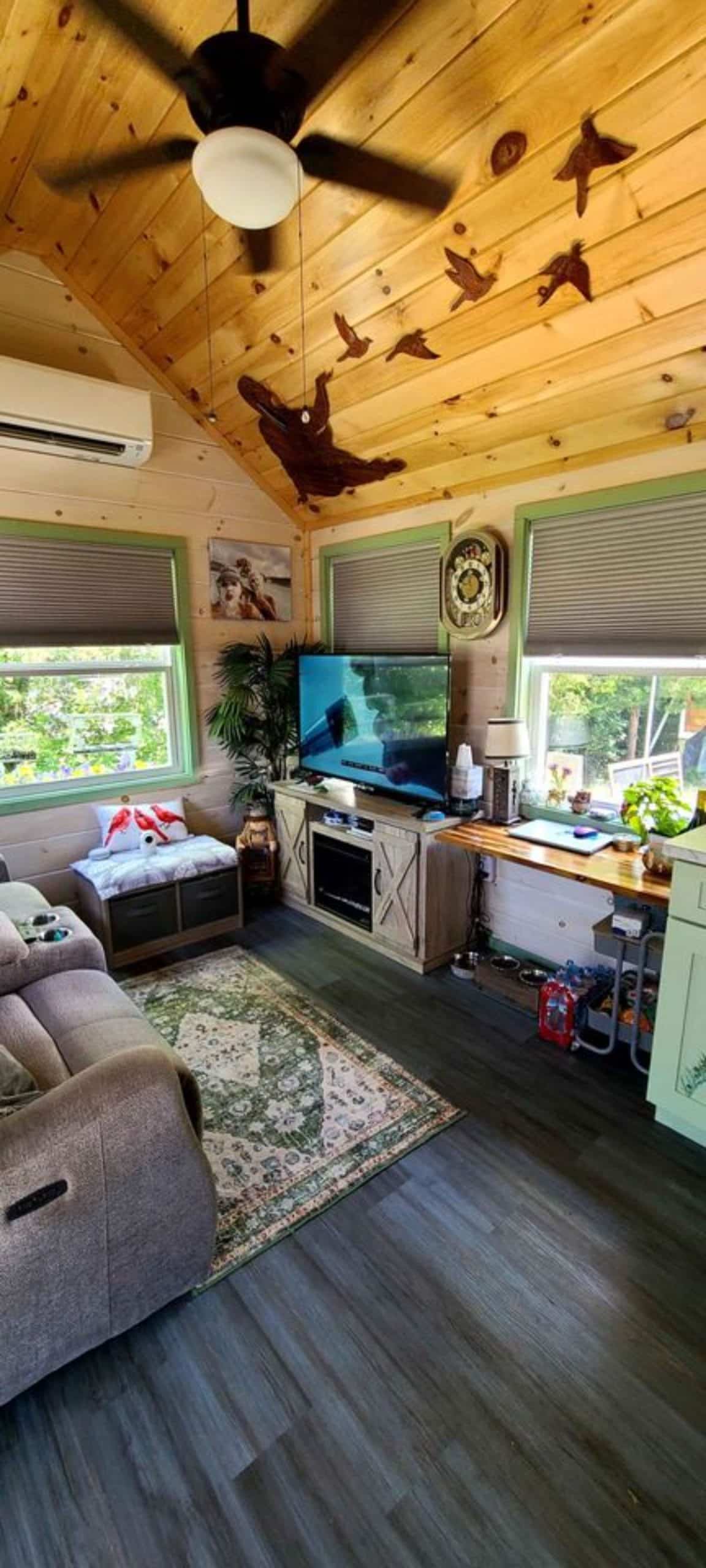 an entertainment unit with wall mounted TV set in living area of mountain tiny home