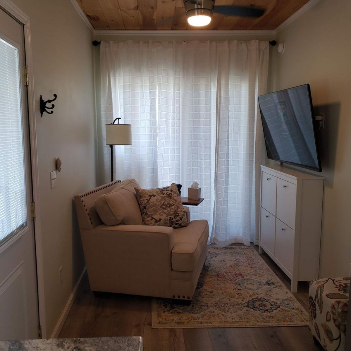 living area of container tiny home has a couch, entertainment unit and wall mounted TV set