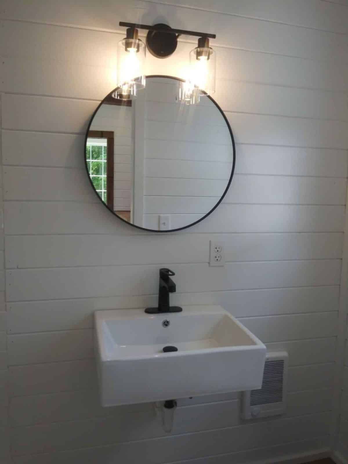 sink with mirror in bathroom of 20’ cottage tiny house