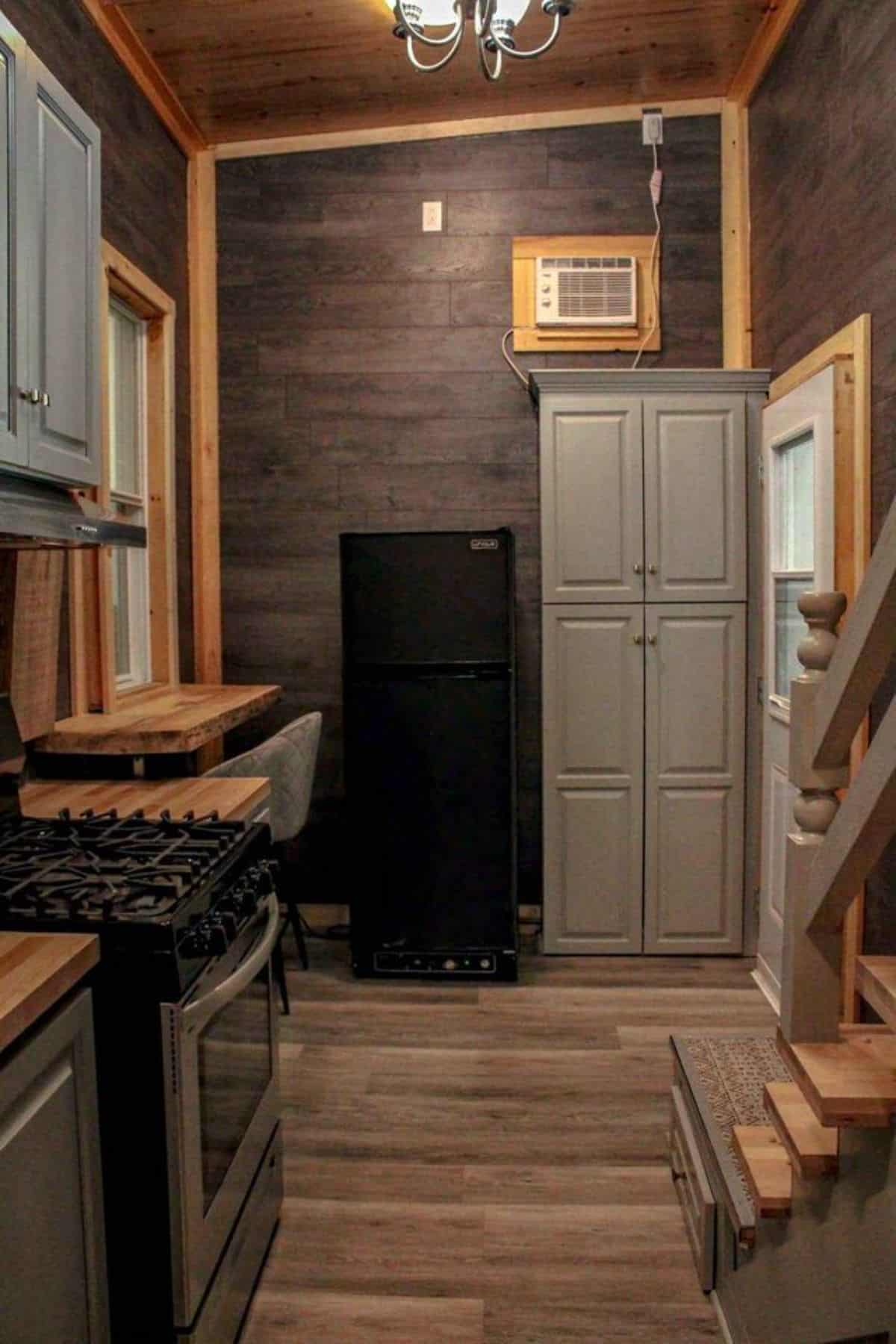 storage cabinets besides refrigerator in the living area of beautiful tiny house
