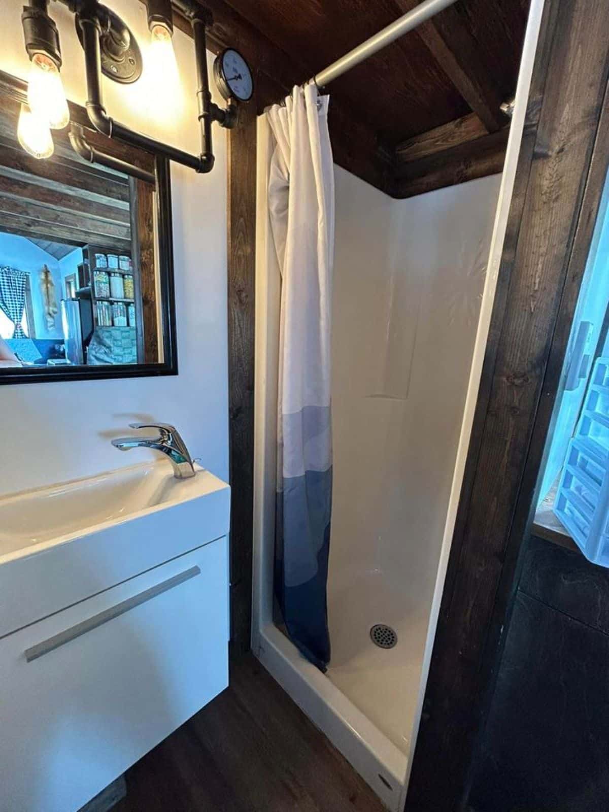 stylish sink with mirror and full length shower area in bathroom