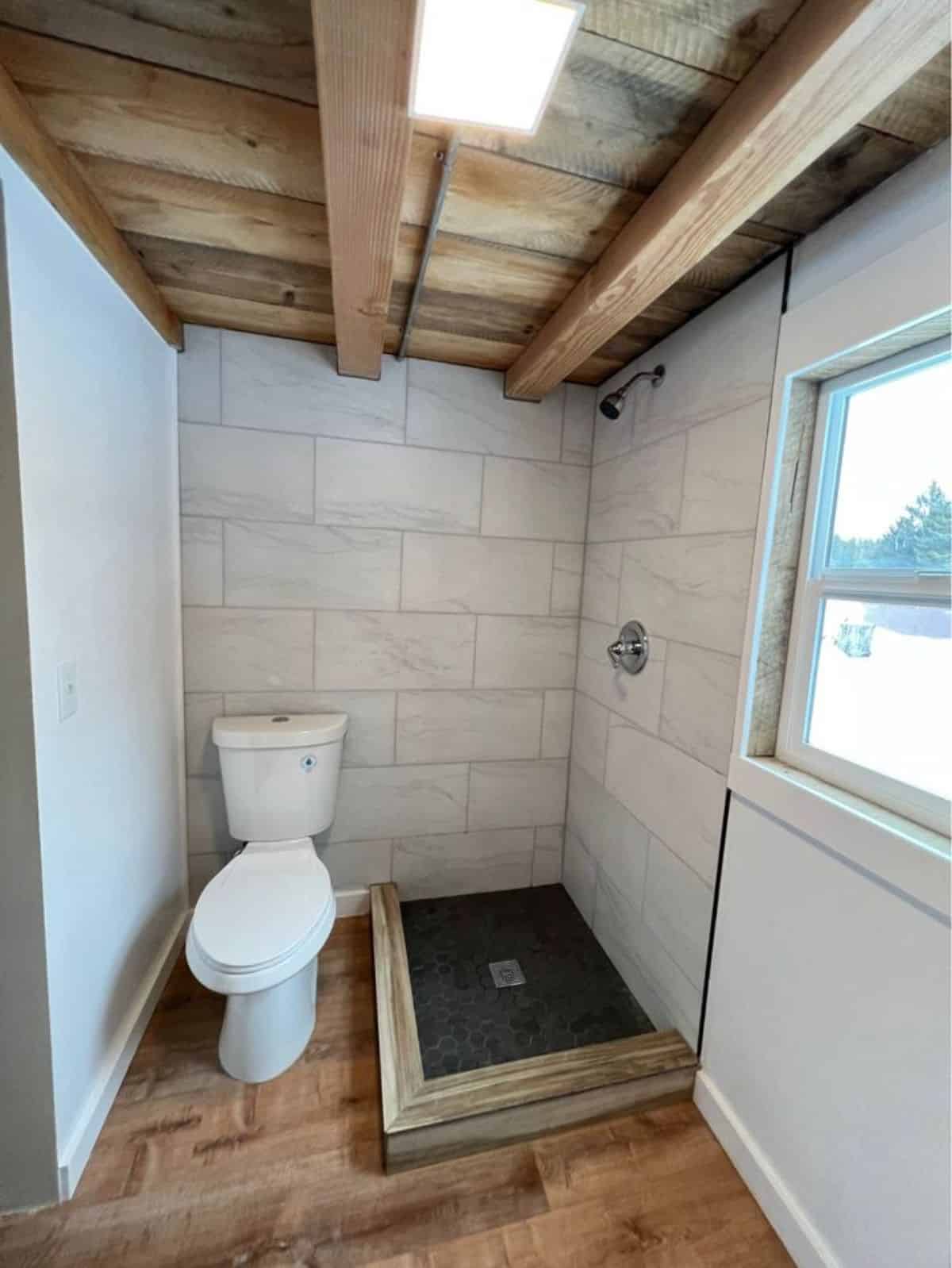 standard toilet, shower area all placed systematically in the bathroom of rustic mini home