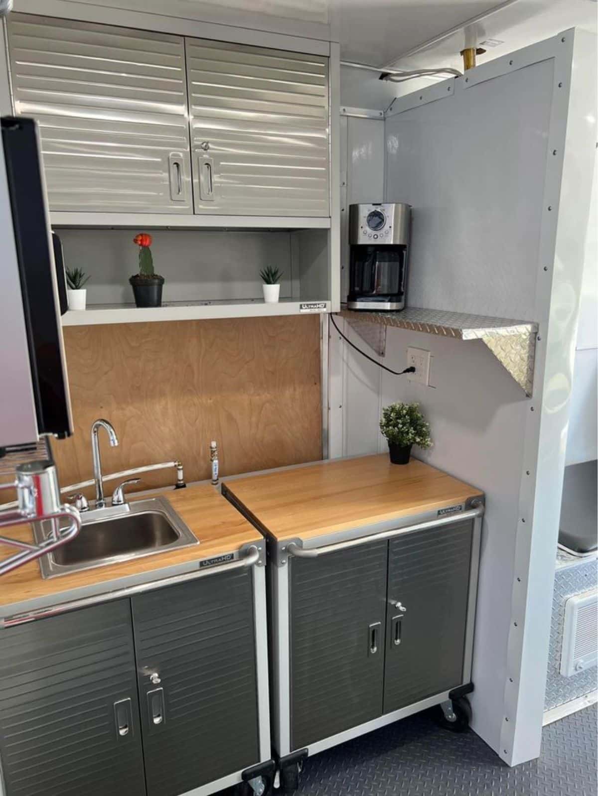 kitchen of tiny trailer home has all the necessary appliances and storage cabinets