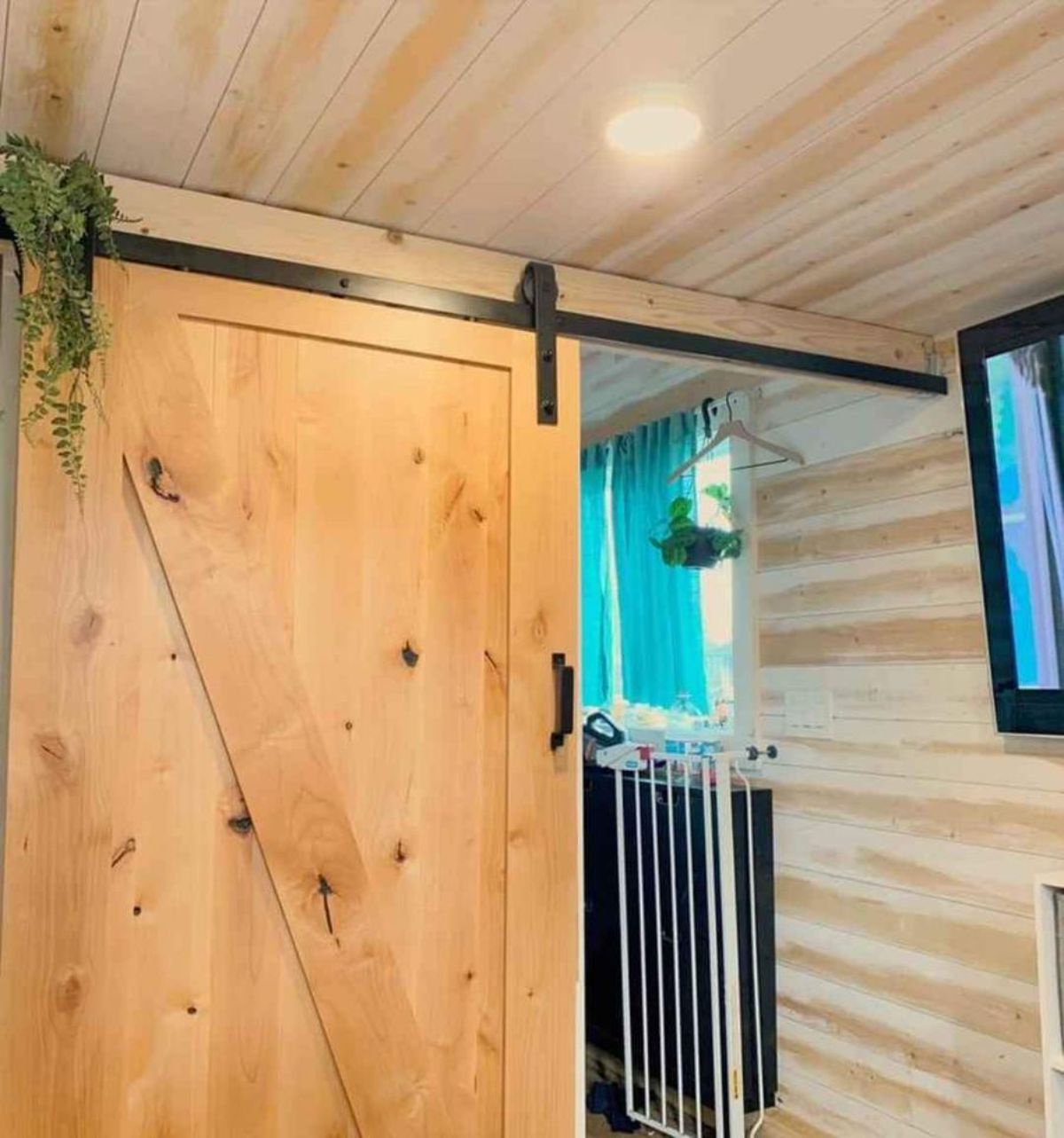 barn door leading to the bathroom of super tiny mobile home